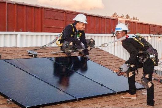 Solar installation employees show off a mock solar roof.