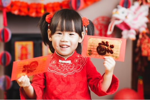 Young girl holding red envelopes.