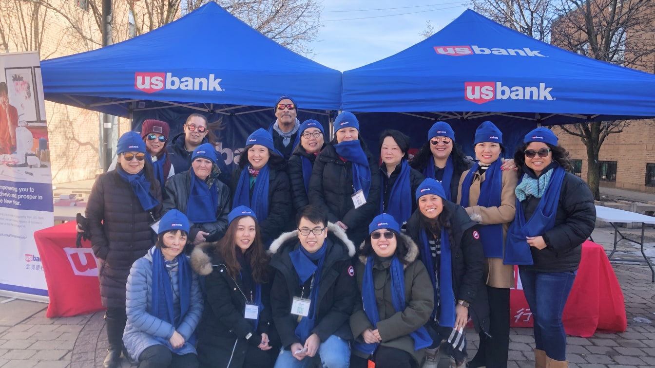 U.S. Bank employees posing in front of branded tents and tables outside at an event.