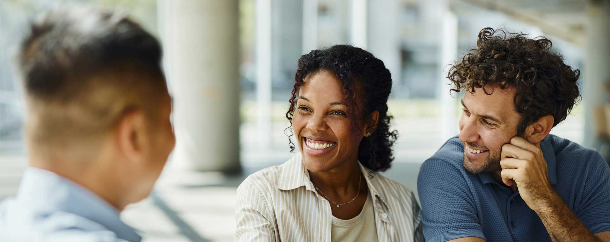 Pareja joven dentro de un banco reuniéndose con un asesor financiero.