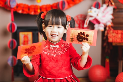 Young girl holding red envelopes.