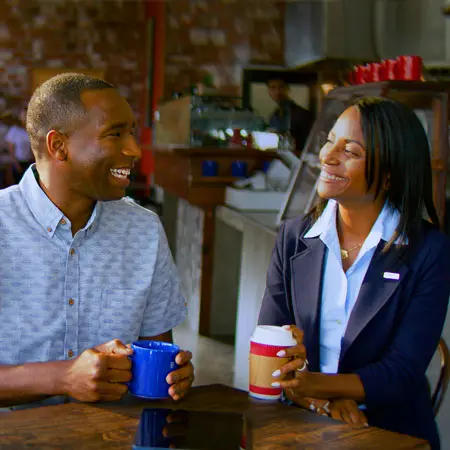 Un representante bancario y un cliente de U.S. Bank conversan sobre finanzas en una cafetería.