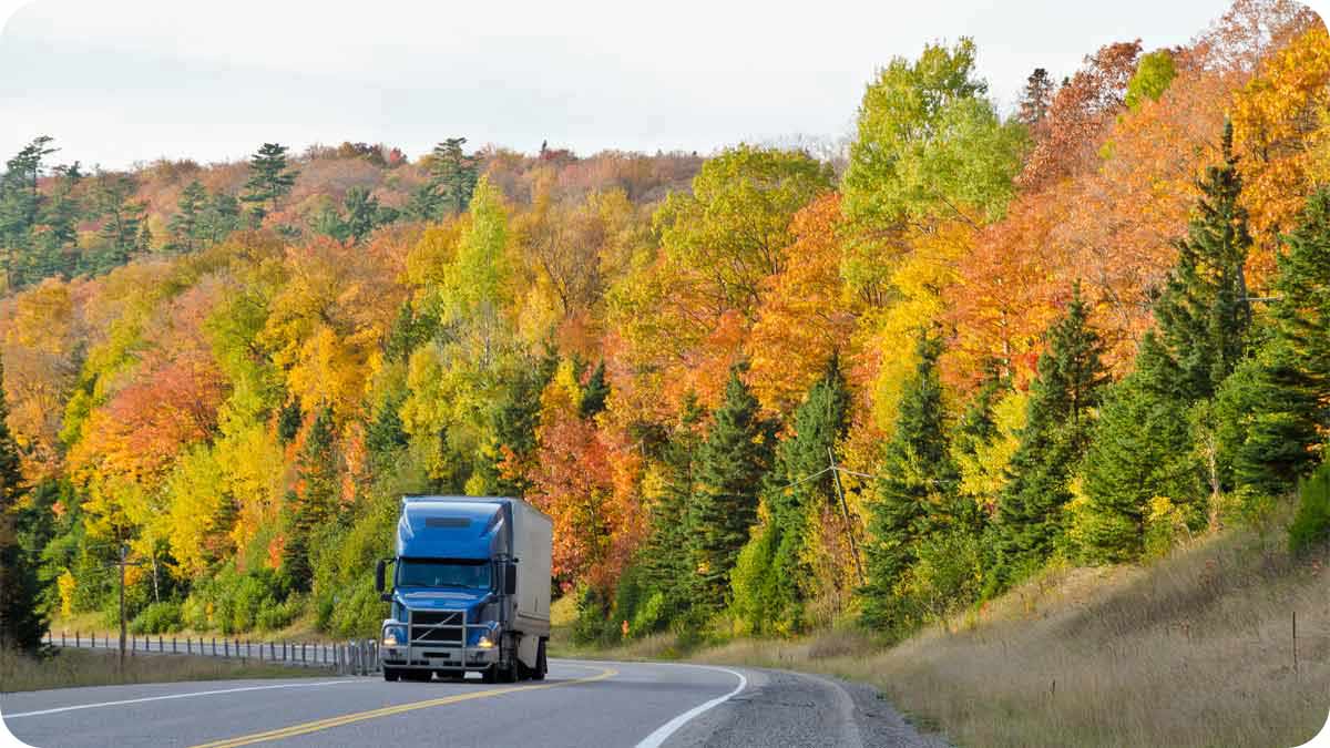 Photo of semi truck driving past autumn landscape