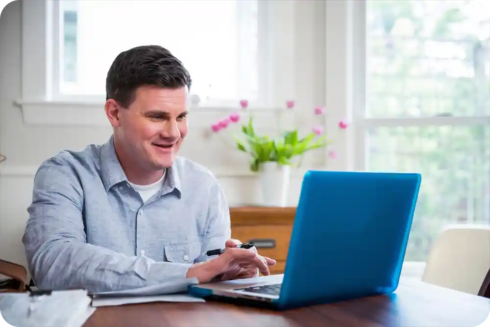 A man at his dining room table working on a laptop
