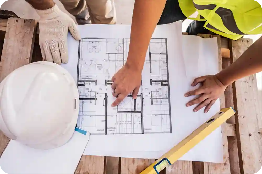 Photo of an architectual blueprint on a table with hands nearby