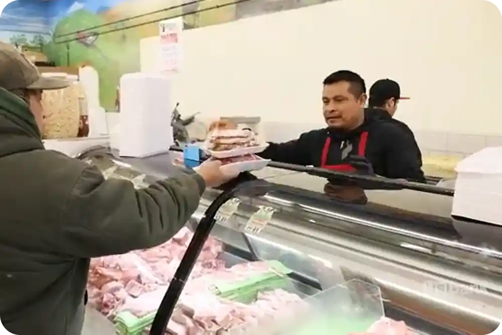 A man serving a customer at a meat counter.