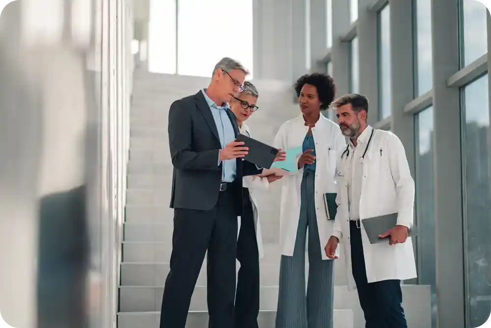 A man in a suit talking to several people wearing medical scrubs