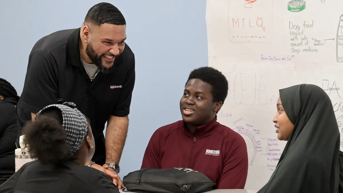 Man with small group of high school students in classroom.