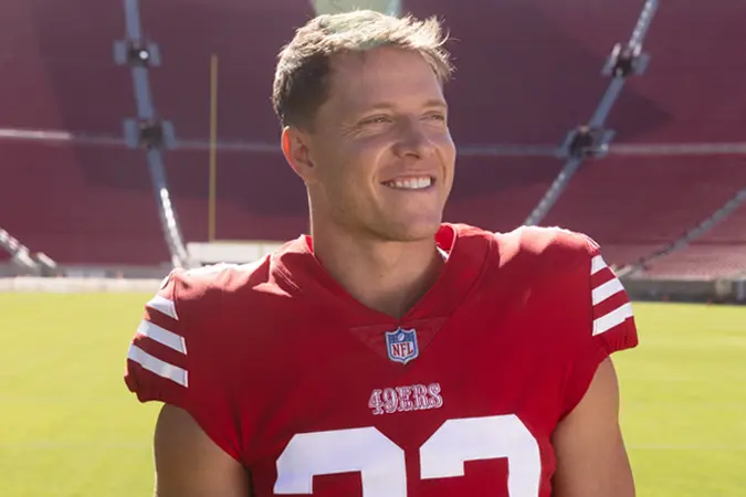 Christian McCaffrey stands on the field with stadium lights in the background.