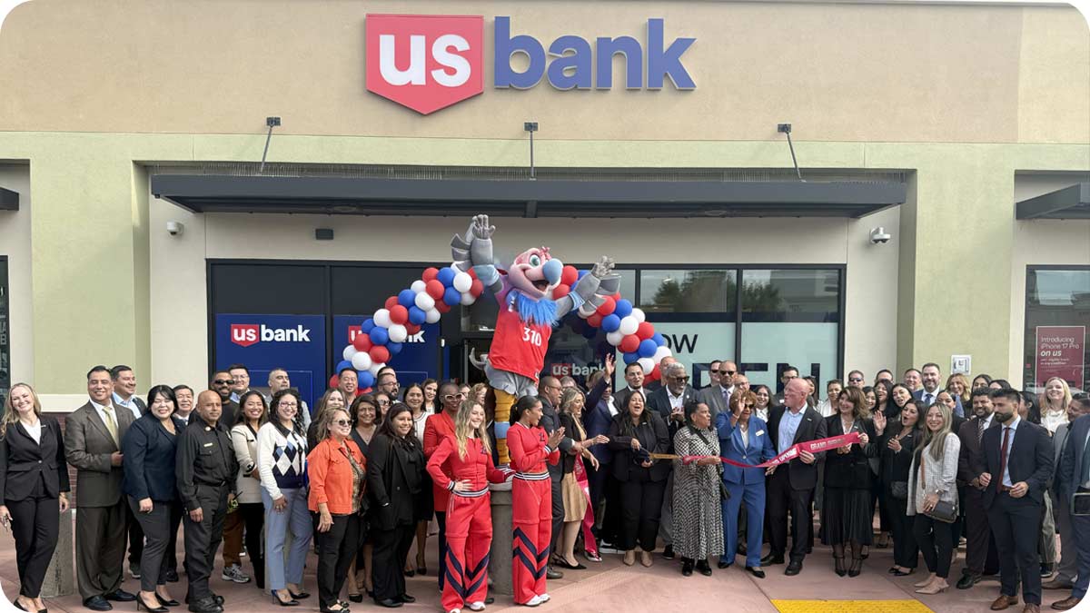 Photo of a large group of people with a balloon arch outside of a U.S. Bank branch