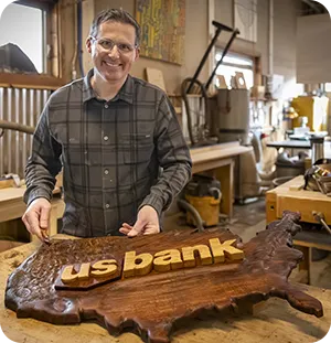 Man with a carved wooden map of the United States that features the U.S. Bank logo.