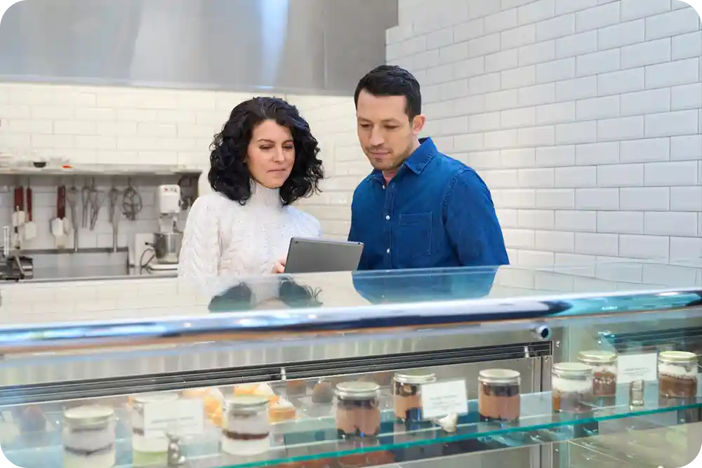 two people behind a counter at a restaurant