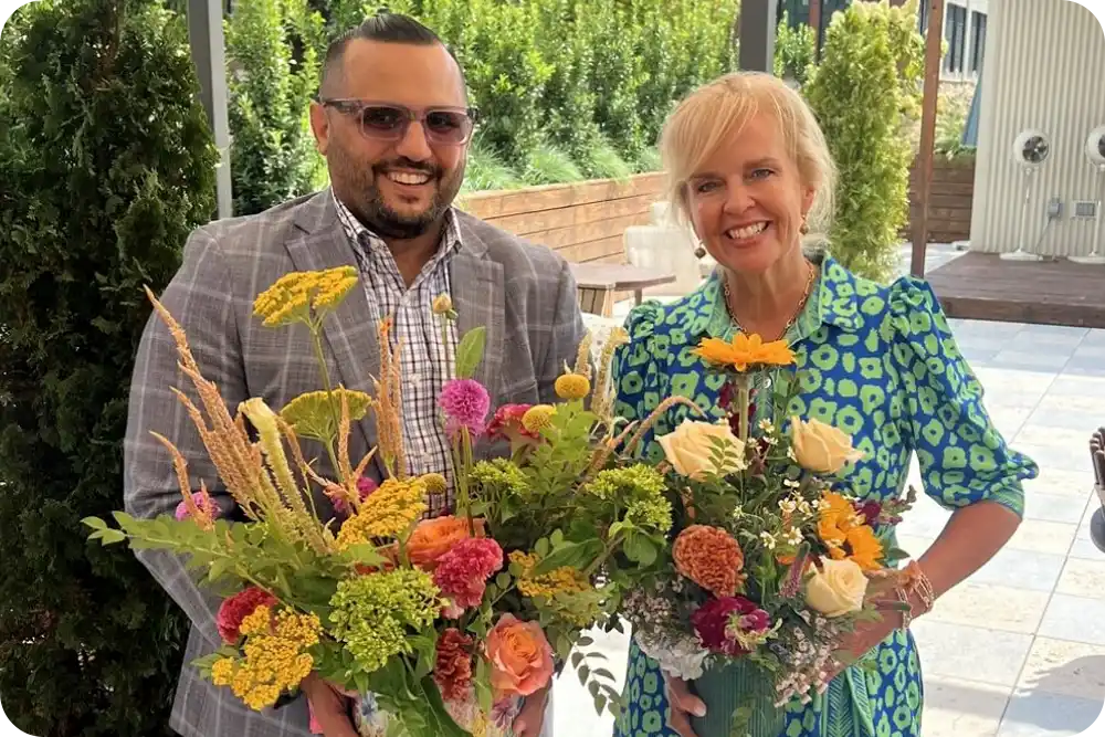 A man and woman holding floral arrangements.