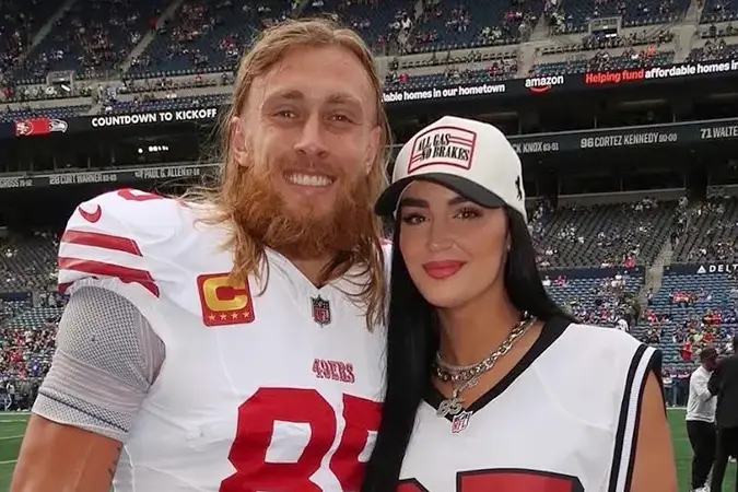 George and Claire Kittle pose for a photo on the football field after a game
