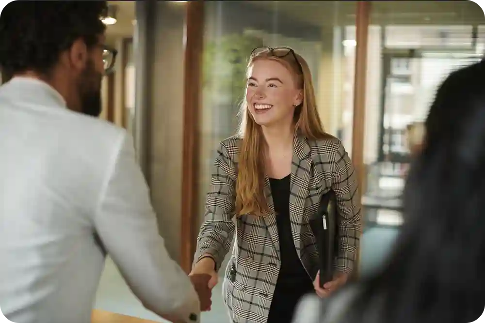 A young woman shaking hands with another person in a professional setting