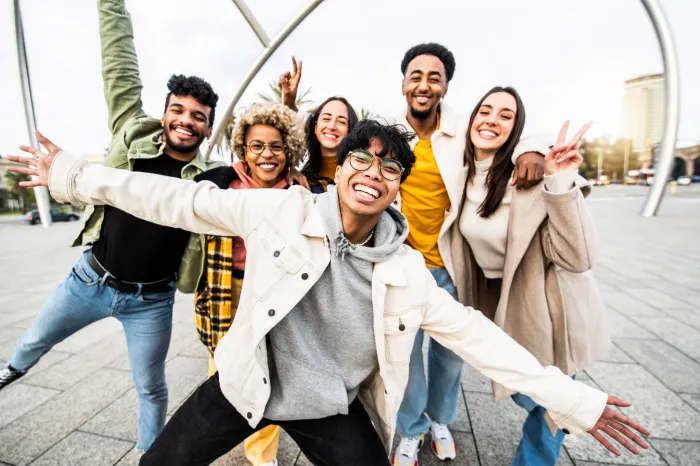 Group of six young adults smiling  together for a candid-looking group photo.