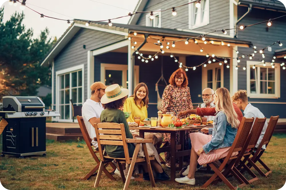 A group of people gathered in the back yard of a home.