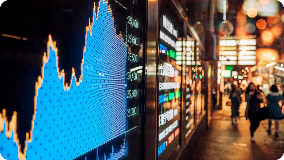 Someone using a tablet in front of a monitor with a lot of data on both.