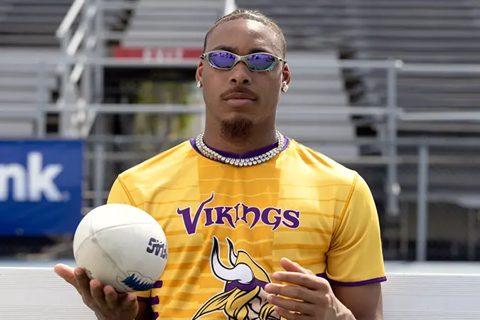 Justin Jefferson balances a football in his hand while facing the camera.