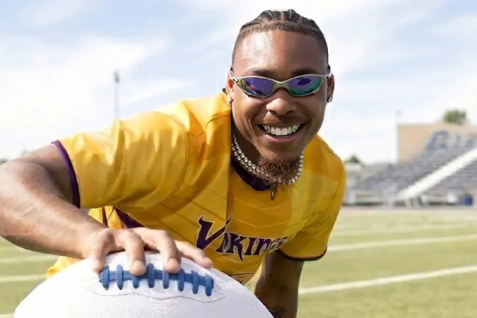 Justin Jefferson holding a football with arms outstretched toward the camera