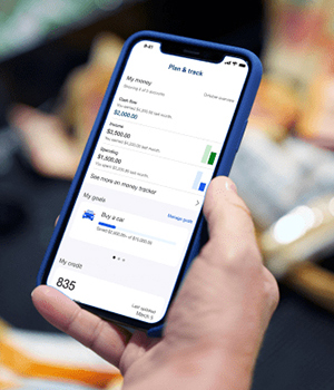 A hand holding a mobile phone showing a banking app.