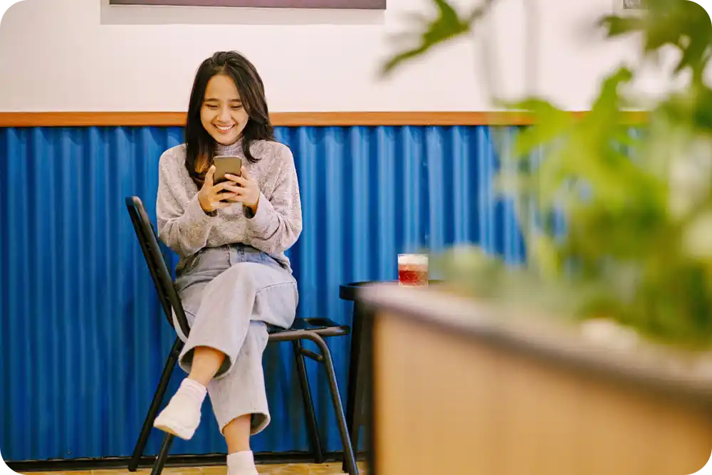 Photo of a woman sitting in a chair, looking at her phone