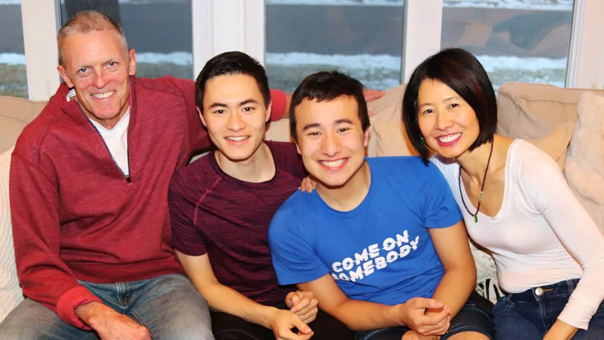 A father, two sons and mother smiling together while sitting on a couch