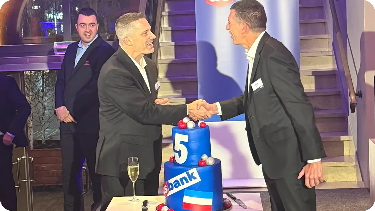 Two men shaking hands with a decorated cake that says U.S. Bank 5 nearby
