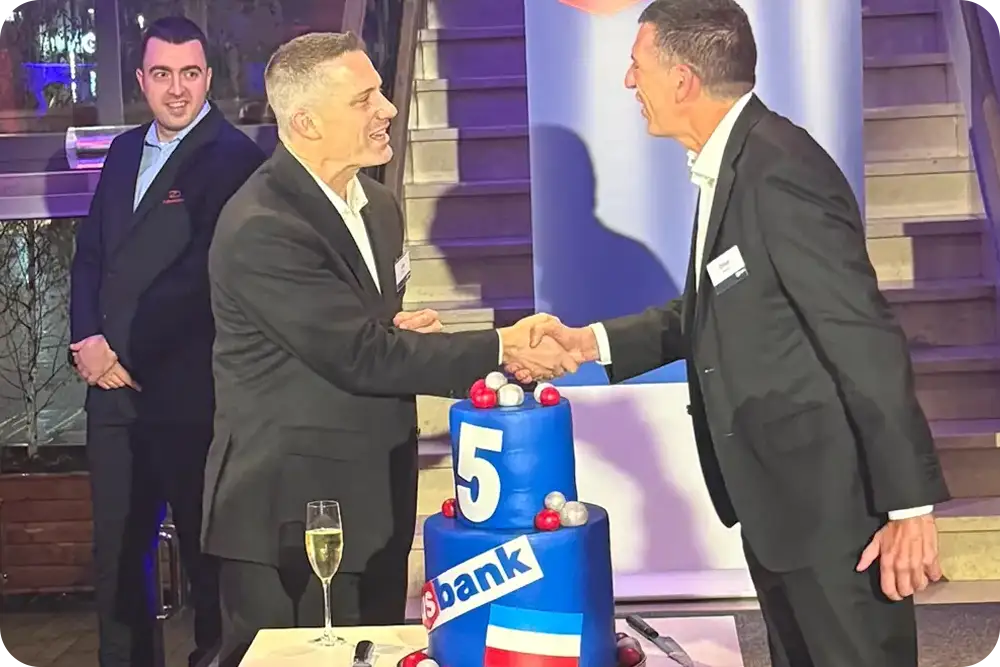 Photo of two men shaking hands with a cake that says U.S. Bank 5 nearby