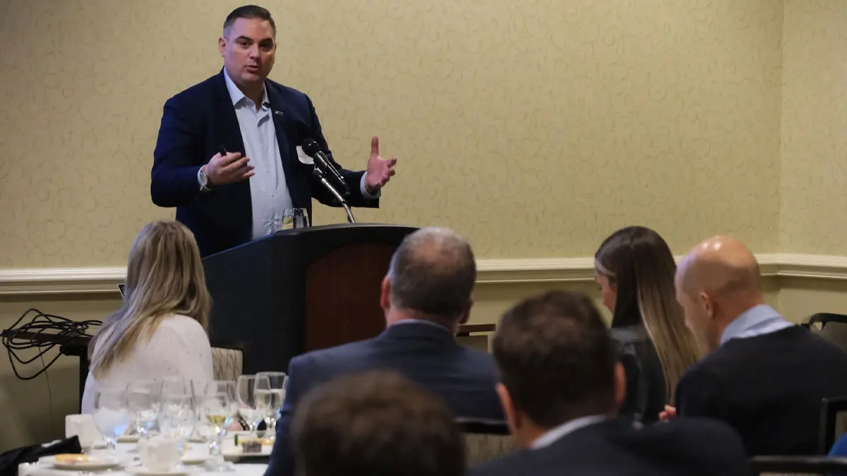 Photo of man speaking at podium to classroom of students.