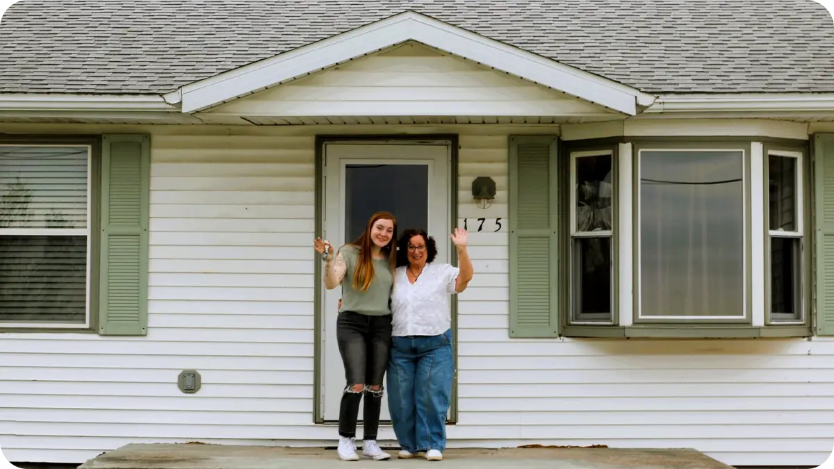 Two women standing on the porch of a house.