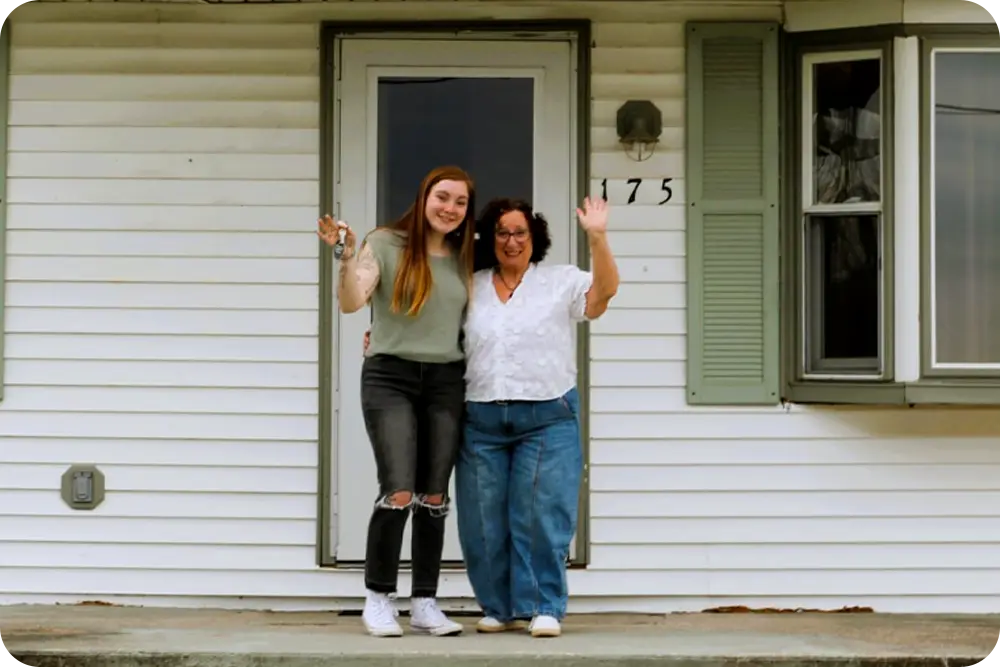 Two women standing on the front porch of a house.