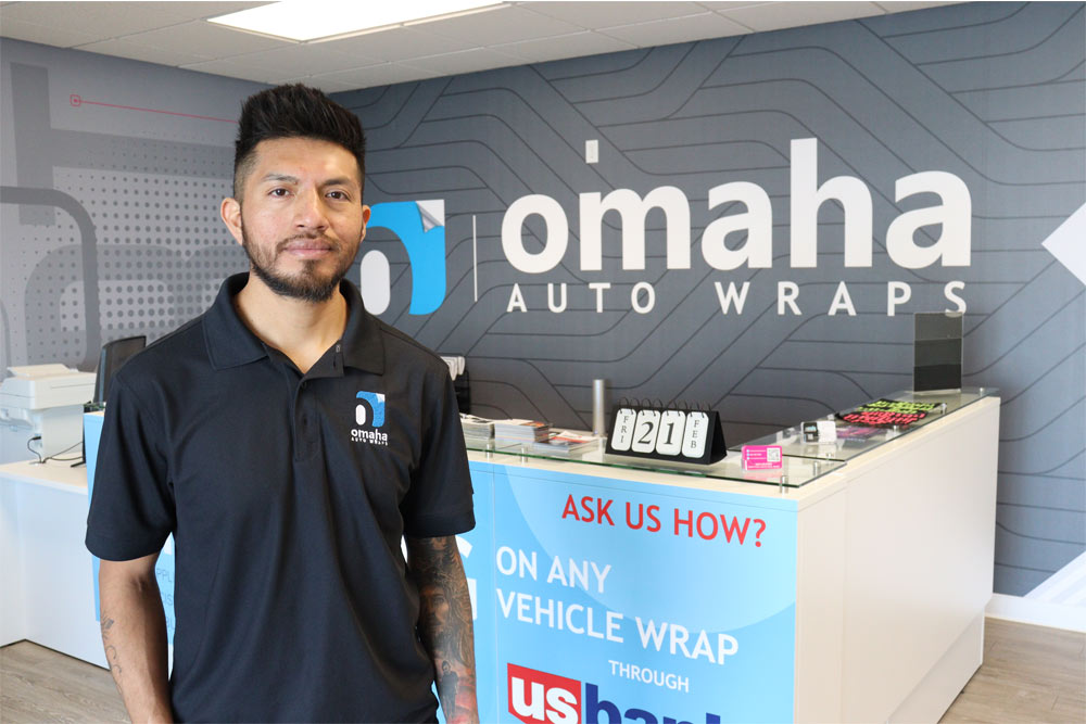 A man standing in front of the counter at an auto wraps business.