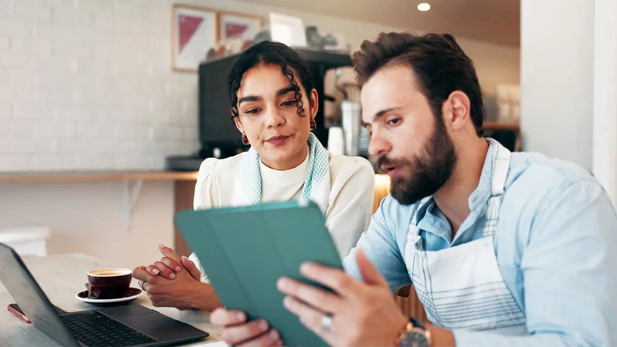 A man and woman at a restaurant looking at a tablet