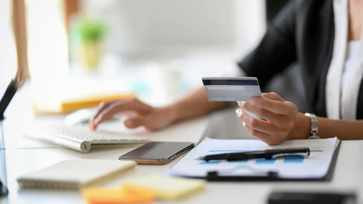 Photo of a woman's hand holding a credit card, poised to make a transaction