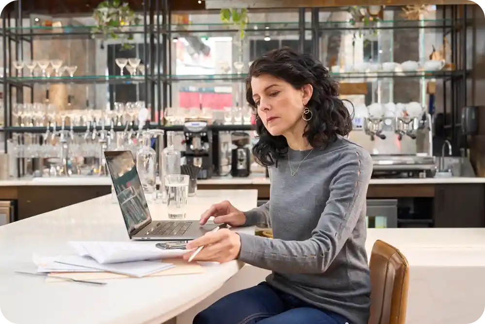 Woman paying bills on a laptop in a restaurant setting