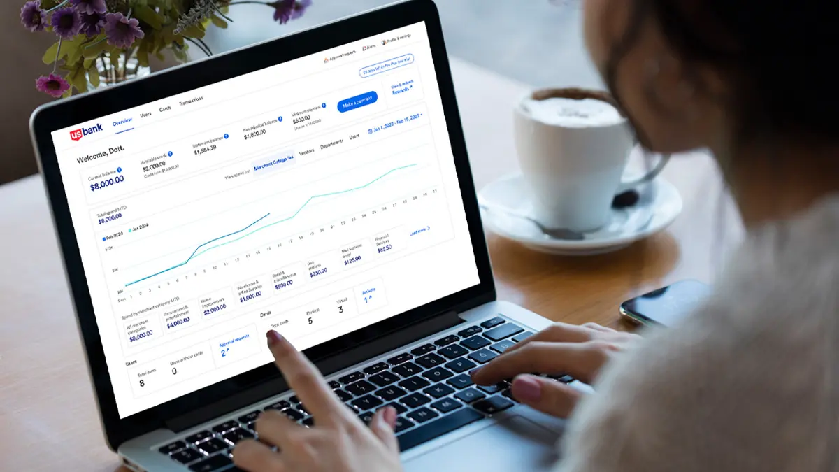 View over the shoulder of woman looking at laptop with Spend Management interface on screen.