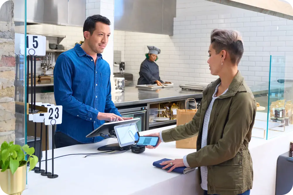 A woman using her phone to make a purchase at a restaurant.