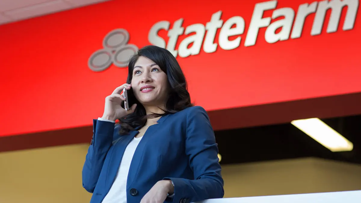 Woman on mobile phone standing in front of State Farm logo