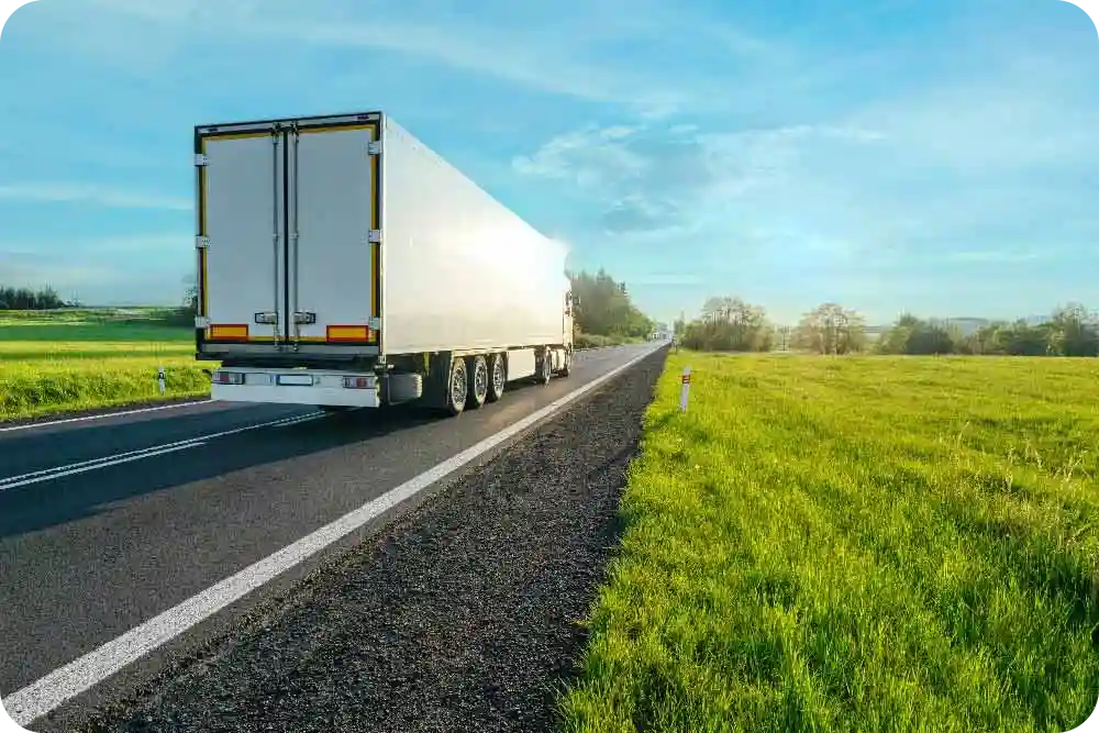 A semi truck driving on a highway in a summertime setting