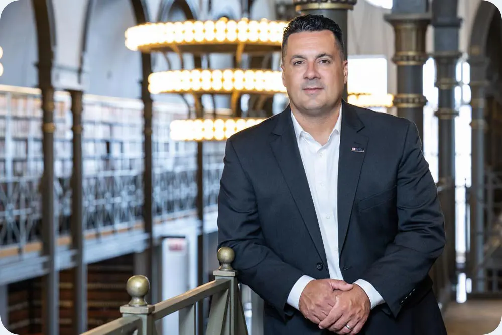 Man in business suit standing in front of an ornate lobby