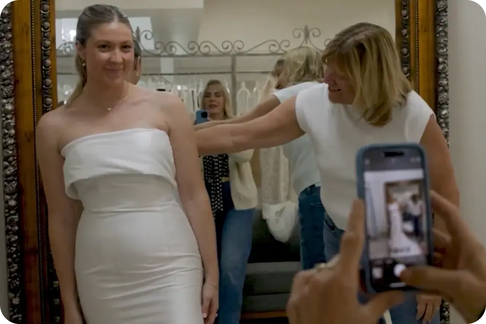 A woman trying on a wedding dress as her family takes a photo