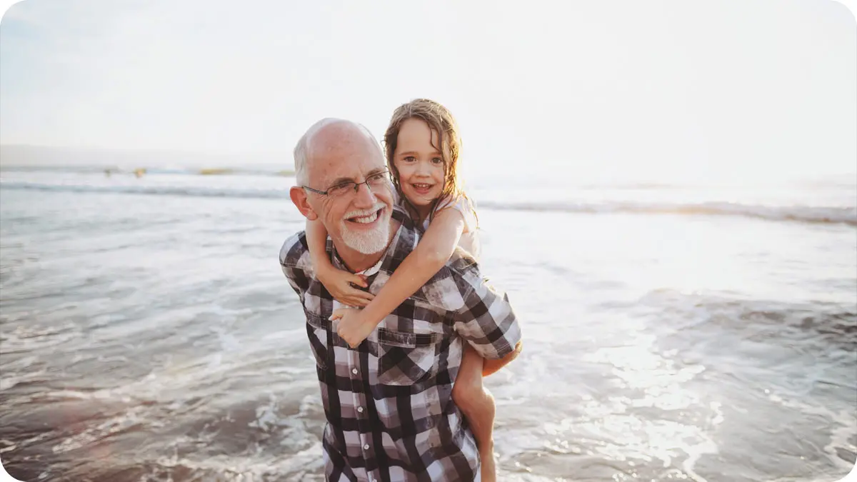 Grandfather and granddaughter playing in waves at the beach