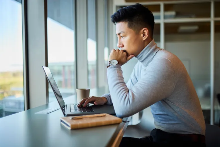 Photo of a serious man at counter with laptop.