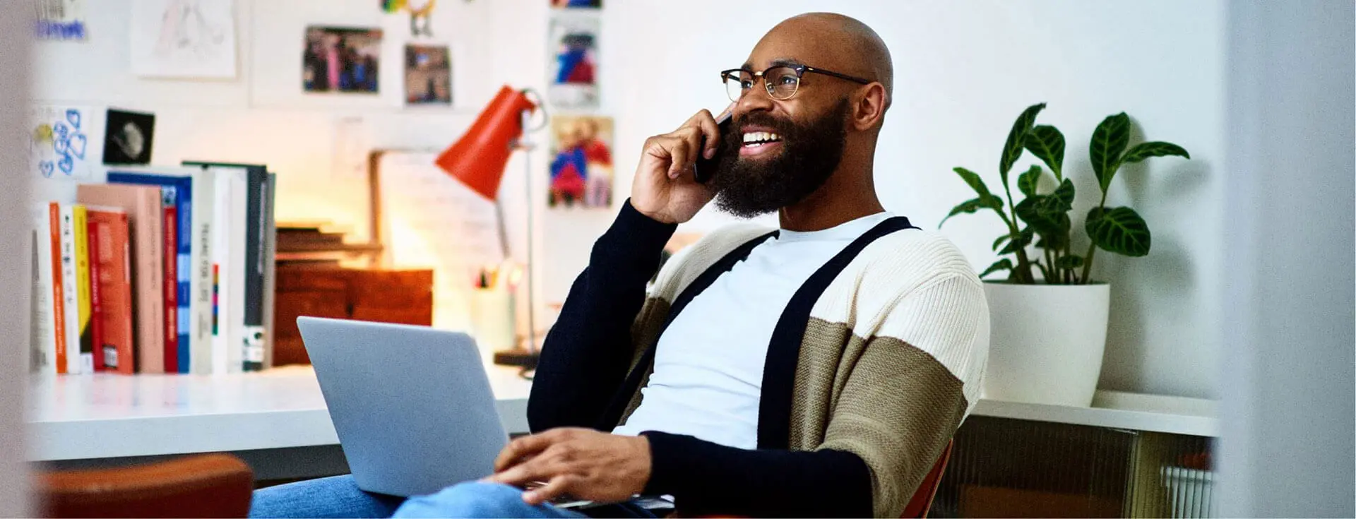 Hombre sonriente hablando por teléfono ante un escritorio.