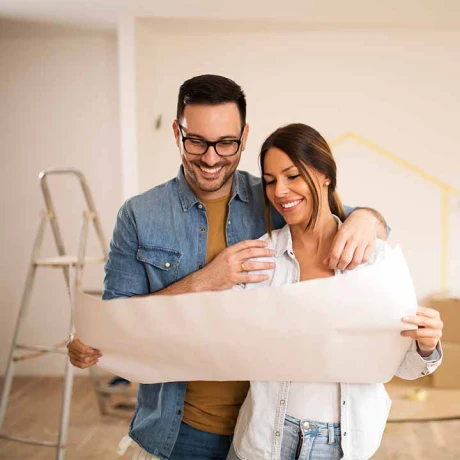 A cheerful couple in front of their new home, representing the rewarding experience of becoming homeowners.