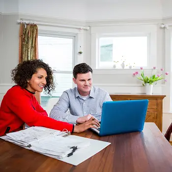 Couple sitting at table looking at computer
