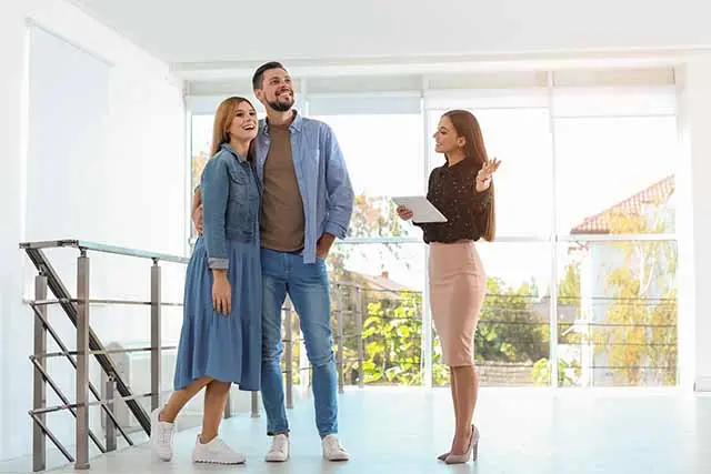 A couple explores an open house with a real estate agent, discussing mortgage market trends