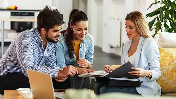 Three people looking at a laptop, discussing customized partnerships for HFA lending.