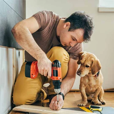 A man drills into wood while working on a home improvement project